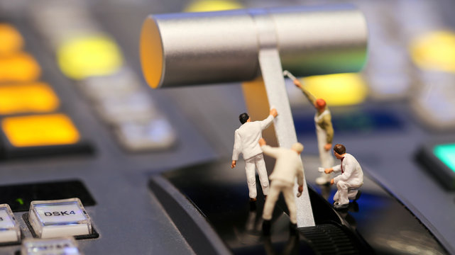 Miniature people : worker painting on switcher control of Television Broadcast,color buttons