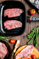 raw meat for steak with rosemary and tomato on table top view