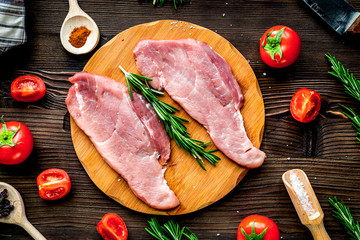 raw meat for steak with rosemary and tomato on table top view