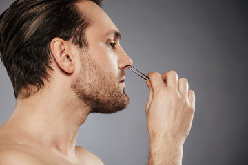 Side view portrait of a confident man removing nose hair