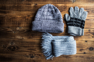 Fototapeta na wymiar grey winter hat gloves scarf on a wooden bacground