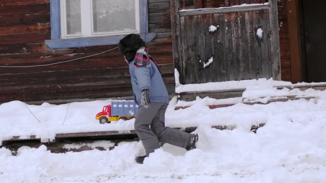 A russian boy is playing with a toy car