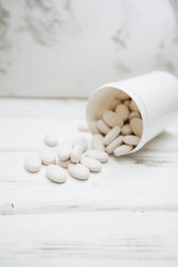 Animal pet care. Vitamins pills for pets in a cup on white board background, closeup. Pet care and veterinary concept