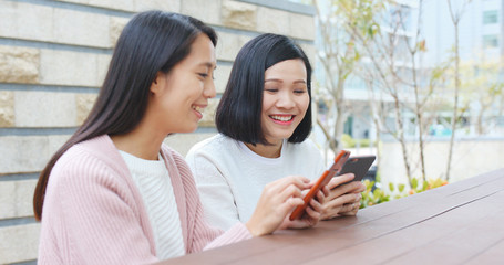 Girl Friends using mobile phone and talking together