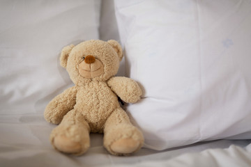 Sleeping teddy bear on white bed.