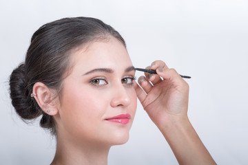 Fototapeta premium Young beautiful woman applying make-up by make-up artist isolated on white.