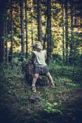 Little Girl Sitting Alone on a Rock in Forest