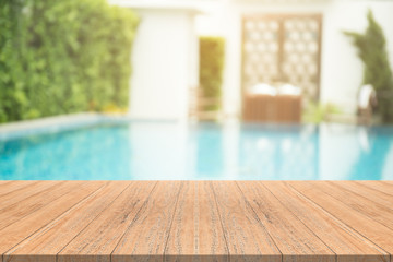 Empty wooden table in front with blurred background of swimming pool - 191350124