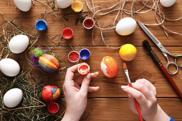 Painting colorful easter eggs, top view on wood