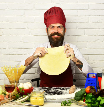 Chef makes pizza. Cook with happy face in burgundy uniform