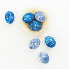 Blue Speckled Easter Egg and nest on white background. Easter holiday. Flat lay. Top view