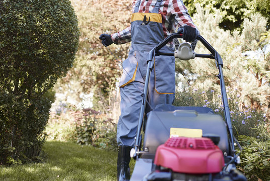 Unrecognizable man turning on mower .