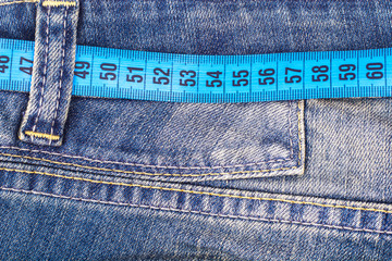 Concept of healthy lifestyle, weight loss. Jeans with measuring tape