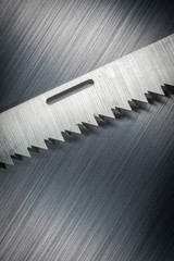 jagged edge saw blade on brushed metal background texture