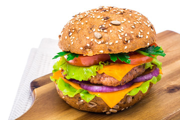 Delicious sandwich with cheddar, meat and salad on cutting board.