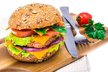 Delicious sandwich with cheddar, meat and salad on cutting board.