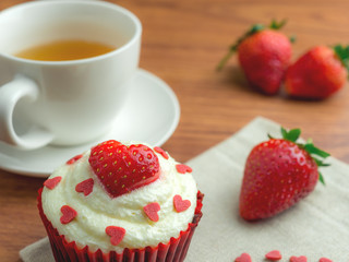 Close-up image of red velvet strawberry cup cake with tea cup, strawberry and heart shape sugar, Valentine concept
