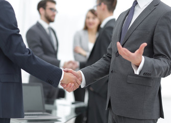 Business partners handshaking over business objects on workplace