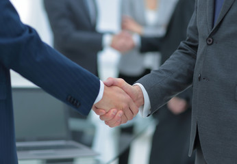 Business partners handshaking over business objects on workplace