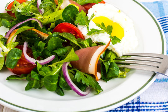 Fresh vegetable salad with ham and fried egg