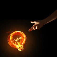 Concept of electricity or inspiration with burning light bulb and creation gesture