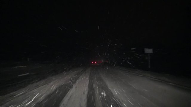 Snowstorm on a slippery road at night. Bad weather for driving a car in heavy snow. Dangerous weather weather in winter for cars. 