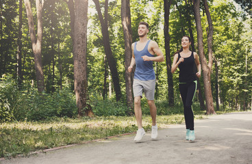 Obraz premium Young couple jogging in green park, copy space