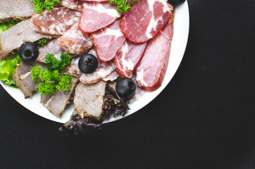 beautifully sliced meat on plate, on dark fabric background