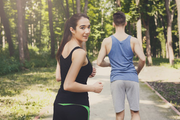 Young couple jogging in green park, copy space