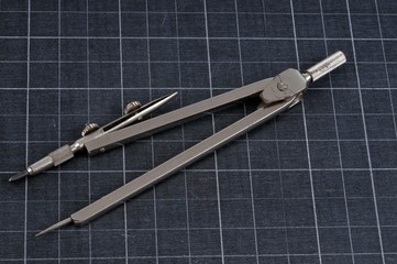 Compas posé sur une ardoise quadrillée 