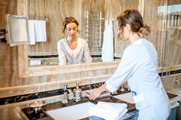 Fototapeta premium Young chambermaid in uniform cleaning a bathroom in the hotel