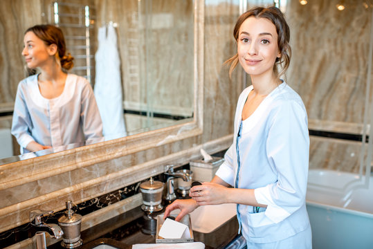 Young chambermaid in uniform cleaning a bathroom in the hotel