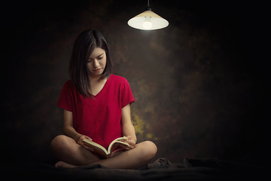woman reading book into the night 