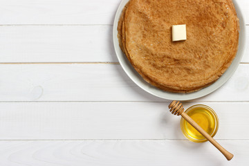 Pancakes with honey and butter on a wooden background