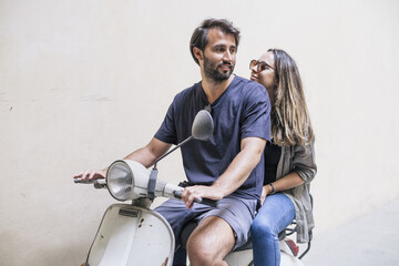 Plakat Loving couple riding an old scooter. The man is seated in front, while the woman is behind