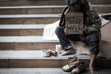 Potrait of homeless people sitting with help papaer sign
