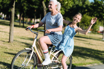 Obraz premium Absolute freedom. Nice positive young girl sitting on the bike and not holding on to it while feeling freedom