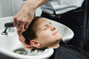 a boy is washed by the hairdresser in the barbershop