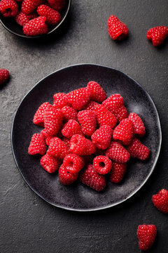 Fresh raspberries on a black bowl. Top view