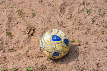 Old football leaked left in the sand field.
