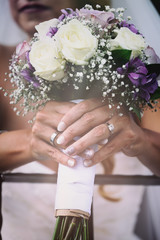 Obraz na płótnie Canvas Bride holding wedding bouquet showing off her wedding rings