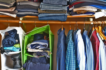 Private house closet with well organized casual man clothes. Man wardrobe with variety of shirts...