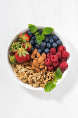 breakfast bowl with fresh berries, granola and almond, vertical top view