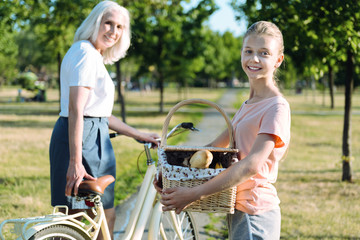 Absolutely prepared. Delighted cute positive girl holding a picnic basket and smiling while being prepared for a picnic