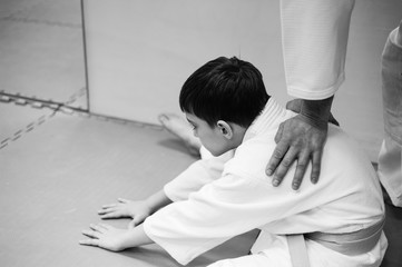 A boy in a kimono has an aikido training with a coach