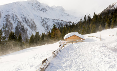 Panoramic view of idyllic winter wonderland with mountain tops and traditional mountain chalet in the Dolomites