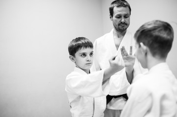 Boys in a kimono have an aikido training with a coach