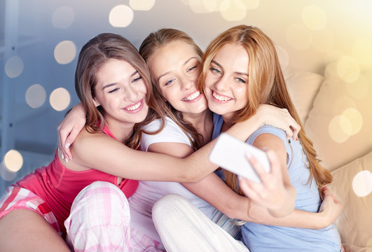 teen girls with smartphone taking selfie at home