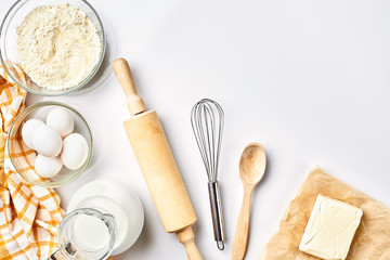Preparation of the dough. A measurement of the amount of ingredients in the recipe. Ingredients for the dough: flour, eggs, rolling pin, whisk, milk, butter, cream. Top view, space for text
