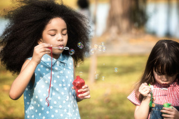 Children are happy to play blow soap bubbles in the garden. Soft focus concept.